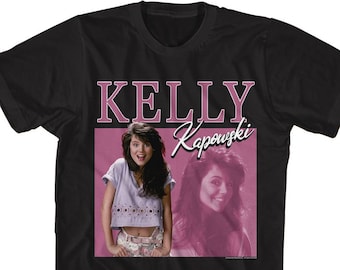 May include: Black t-shirt with a pink and white image of Kelly Kapowski from the TV show Saved by the Bell. The image features Kelly in two different poses, with the text "Kelly Kapowski" in pink.