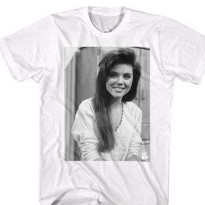 May include: Black and white photo of a woman with long hair, wearing a white shirt. The photo is printed on a white t-shirt.