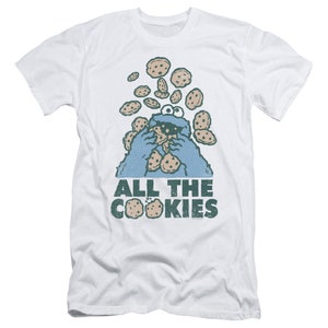 May include: White t-shirt with a blue Cookie Monster character eating cookies. The text "All the Cookies" is printed below the character.