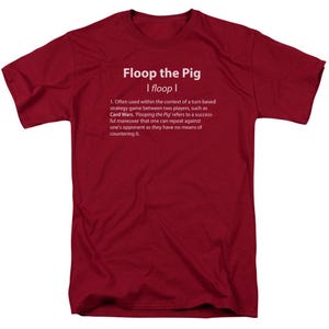 May include: Red t-shirt with white text that reads "Floop the Pig I floop I" and a definition of the term "floop the pig" in the context of a turn-based strategy game.