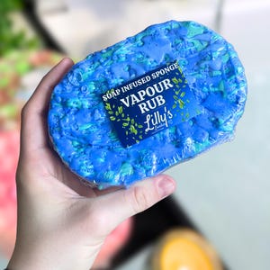 May include: A blue soap infused sponge with a label that reads "Soap Infused Sponge Vapour Rub Lilly's Lotions".