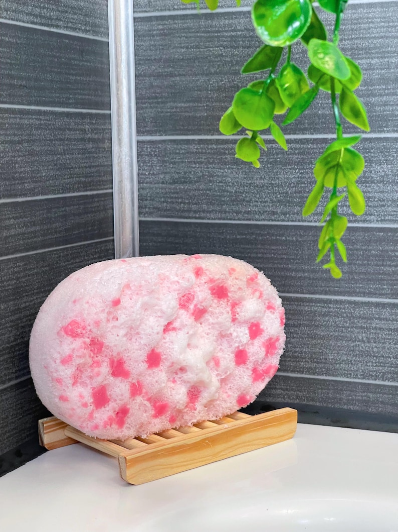 A Soap Infused Sponge after being used. It is set on a drying rack on the side of the bath tub, still covered in some soapy bubbles. These sponges can be used daily for up to three weeks while still retaining soap and a great fragrance. They just need to be set down to dry after use, and then they are ready to use again.
