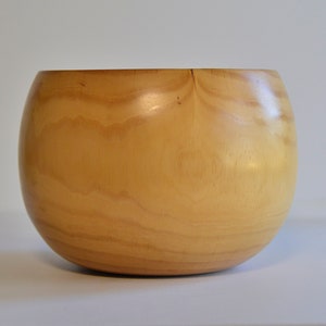 May include: A large, round wooden bowl with a light brown color and a smooth, polished finish.