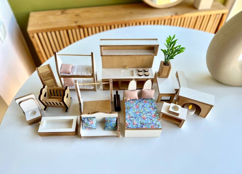 Puede incluir: Un conjunto de muebles en miniatura para casa de mu&ntilde;ecas con acabado blanco y madera. El conjunto incluye una cama, una cuna, una litera, un sof&aacute;, un inodoro, una ba&ntilde;era, un lavabo, una chimenea y una planta.