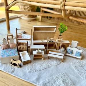 Puede incluir: Un conjunto de muebles de madera en miniatura para una casa de mu&ntilde;ecas, que incluye una cama, una litera, un sof&aacute;, una mesa, una ba&ntilde;era, un caballo de balanc&iacute;n, un armario de cocina y una chimenea. Los muebles est&aacute;n pintados en tonos de madera natural y tienen un estilo r&uacute;stico y de granja.
