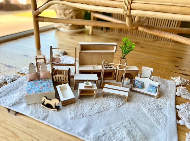 Puede incluir: Un conjunto de muebles de madera en miniatura para una casa de mu&ntilde;ecas, que incluye una cama, una litera, un sof&aacute;, una mesa, una ba&ntilde;era, un caballo de balanc&iacute;n, un armario de cocina y una chimenea. Los muebles est&aacute;n pintados en tonos de madera natural y tienen un estilo r&uacute;stico y de granja.