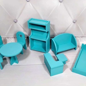 Op de afbeelding: Een turquoise poppenhuismeubelset. De set bevat een tafel, stoelen, een boekenplank, een bank, een bed en een bijzettafel. De stoelen hebben hartvormige uitsparingen. De meubels zijn van hout. Afmetingen in cm.