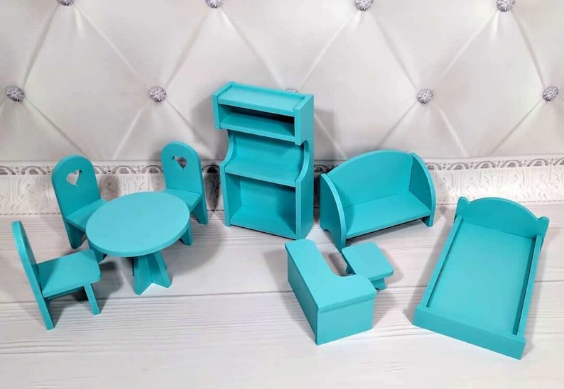 Op de afbeelding: Een turquoise poppenhuismeubelset. De set bevat een tafel, stoelen, een boekenplank, een bank, een bed en een bijzettafel. De stoelen hebben hartvormige uitsparingen. De meubels zijn van hout. Afmetingen in cm.