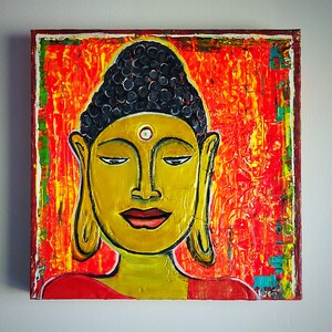 May include: A painting of a Buddha with a yellow face and a black and white headdress. The background is a vibrant orange and red with hints of yellow and green.