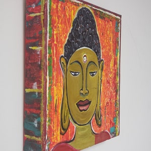 May include: A painting of a Buddha with a red, orange, and yellow background. The Buddha has a black bun and a white dot on their forehead.