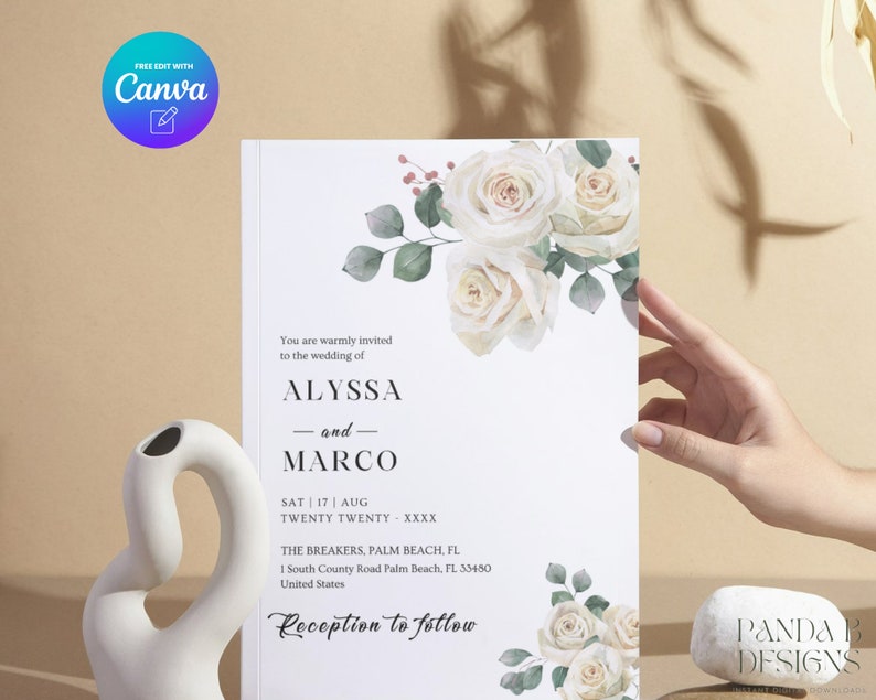 May include: White wedding invitation with a floral design featuring white roses and green leaves. The text reads "You are warmly invited to the wedding of Alyssa and Marco. Sat | 17 | Aug Twenty Twenty XXXX The Breakers, Palm Beach, FL 1 South County Road Palm Beach, FL 33480 United States Reception to follow"