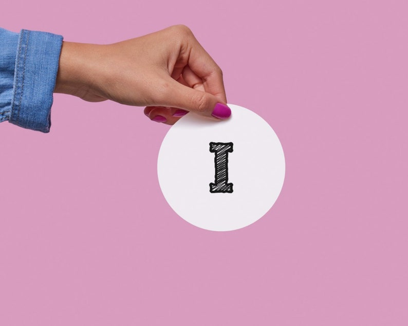 May include: A hand holding a white circle with the letter "I" written in black.