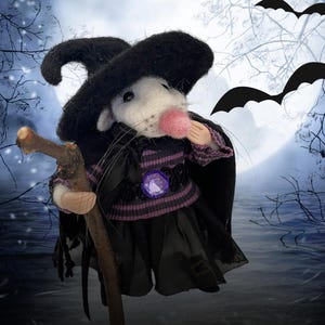May include: A needle-felted white mouse figurine wearing a black witch hat, a purple and black striped sweater with a purple gem accent, and a black skirt. The mouse holds a small wooden branch staff, set against a backdrop of a full moon.