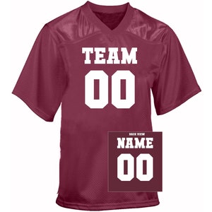 May include: Burgundy football jersey with white lettering. The front of the jersey says "TEAM 00". The back of the jersey says "NAME 00".
