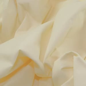 Puede incluir: Primer plano de una tela lisa de color amarillo pálido con pliegues y arrugas suaves.