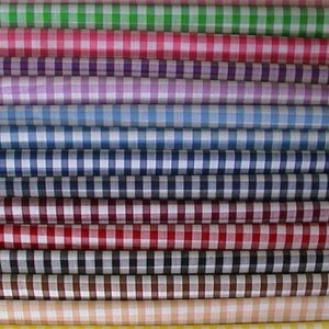 May include: A collection of 14 gingham fabric rolls in various colors, including pink, green, red, blue, and yellow. The fabric is a classic gingham pattern with white squares.