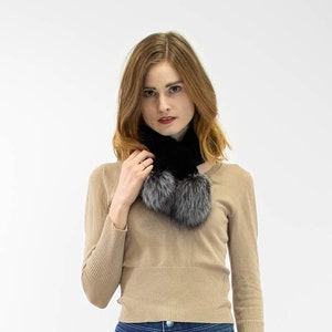 Puede incluir: Una mujer con un suéter beige con una bufanda de piel negra y gris, jeans azules y botas negras con cordones.