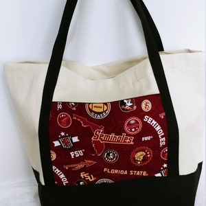 Può includere: Una borsa tote in tela bianca con manici neri e una fodera in tessuto rosso e nero. La fodera presenta un motivo ripetuto di loghi dei Florida State Seminoles e le parole "Florida State" e "Seminoles".