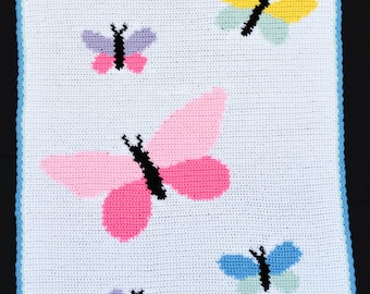 Könnte beinhalten: Eine weiße Häkeldecke mit blauem Rand, auf der fünf bunte Schmetterlinge zu sehen sind. Die Schmetterlinge sind rosa, gelb, lila, blau und grün.