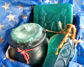 May include: A set of three green and black soap bars in a blue and silver star patterned gift box. The soap bars are shaped like a cauldron, a bottle, and a rectangular bar.