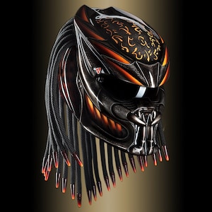 Può includere: Un casco da moto personalizzato con un design Predator. Il casco è principalmente nero con accenti arancioni e oro. Presenta un design del viso dettagliato con una mascella incernierata e dreadlocks con punte rosse.
