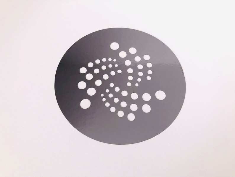 Pu&ograve; includere: Un adesivo circolare grigio con un design stilizzato bianco di un motivo a punti a spirale.