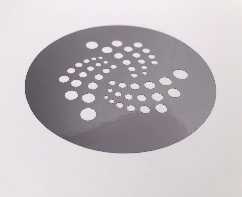 Pu&ograve; includere: Uno stencil circolare grigio con un motivo bianco di punti disposti in forma circolare.