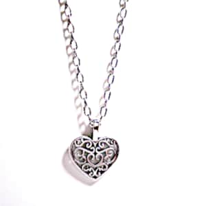 Peut inclure: Un collier en chaîne argent avec un pendentif en forme de cœur délicat et ajouré.