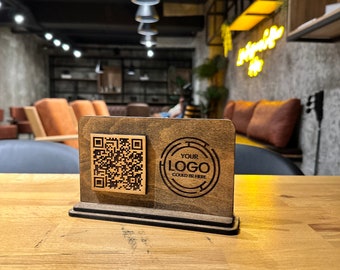 May include: A wooden sign with a QR code and the text "YOUR LOGO COULD BE HERE" in a circle. The sign is on a wooden table.