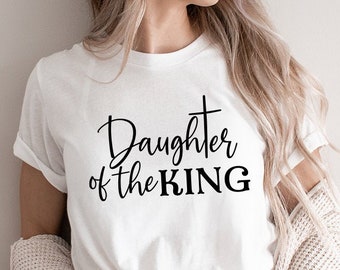 May include: White t-shirt with a black graphic that says "Daughter of the KING" with a cross above the word "KING".