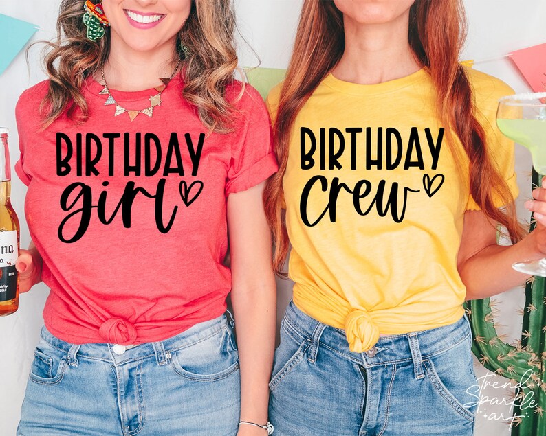 May include: Two people wearing matching t-shirts. The person on the left is wearing a red shirt with the text "Birthday girl" in black. The person on the right is wearing a yellow shirt with the text "Birthday Crew" in black.