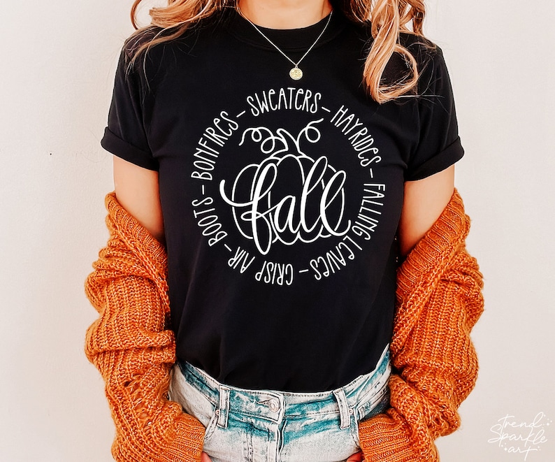 May include: Black t-shirt with a white graphic of a pumpkin and the word "fall" surrounded by text that reads "Crisp Air - Boots - Bonfires - Sweaters - Hayrides - Falling Leaves".