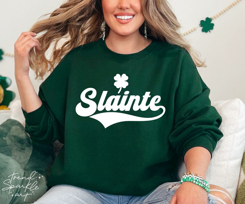 May include: A dark green sweatshirt with a white shamrock and the word "Slainte" in a retro font. The sweatshirt is a comfortable and stylish way to show your Irish pride.