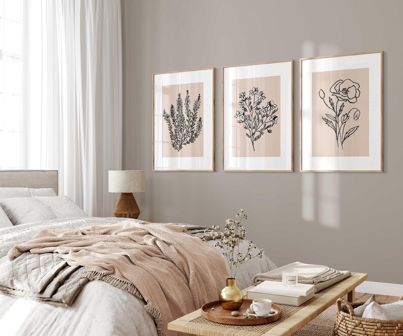 Puede incluir: Tres impresiones enmarcadas de dibujos en blanco y negro de flores sobre un fondo beige claro. Las impresiones est&aacute;n colgadas en una pared gris claro en un dormitorio.