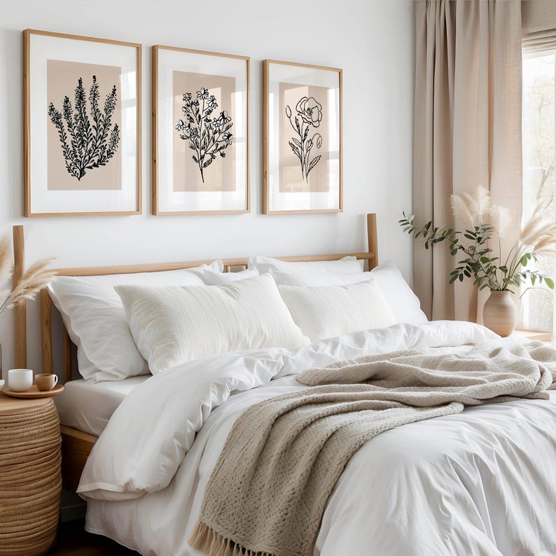 Puede incluir: Una cama blanca con una manta de punto beige y tres dibujos en blanco y negro enmarcados de flores en la pared detr&aacute;s de la cama.