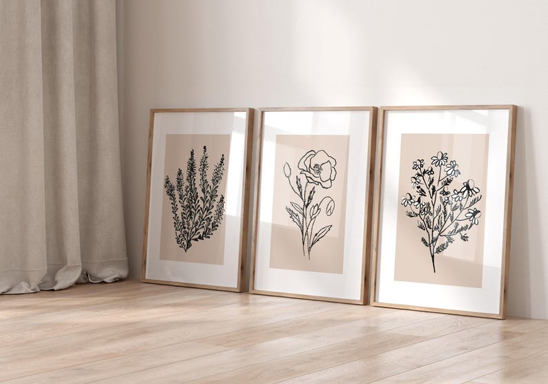 Puede incluir: Tres impresiones enmarcadas con dibujos de l&iacute;nea negra de diferentes flores sobre un fondo beige. Los marcos son de madera clara.