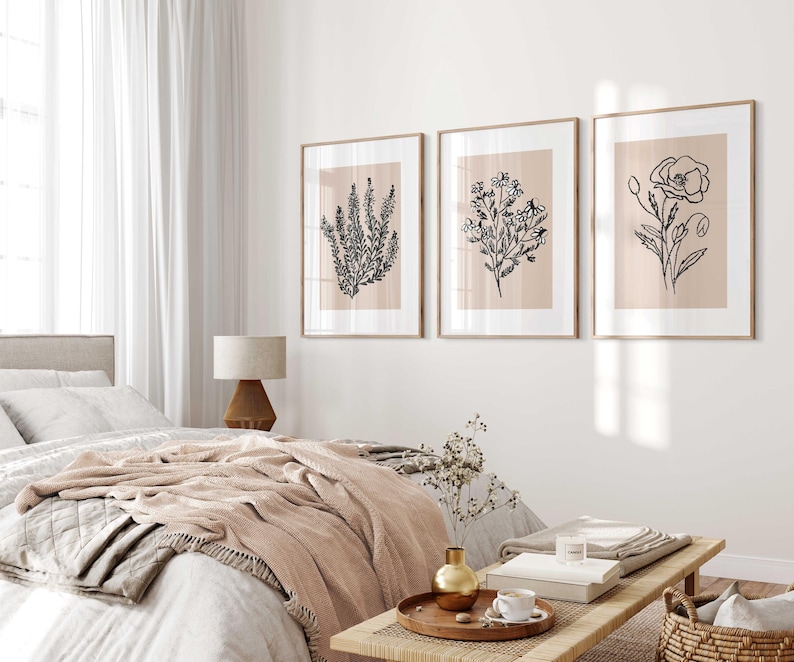 Puede incluir: Tres dibujos en blanco y negro de plantas enmarcados sobre un fondo rosa claro. Los dibujos son de una amapola, un grupo de flores peque&ntilde;as y una rama de lavanda. Los marcos son de madera clara y est&aacute;n colgados en una pared blanca.