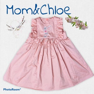 May include: A pale pink sleeveless dress with a ruffled neckline and skirt. The dress has an embroidered floral design on the bodice. The dress is labelled "Mom & Chloe".