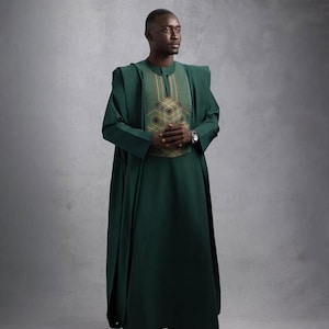 May include: A dark green traditional outfit with intricate embroidery on the chest. The outfit includes a long, flowing robe and matching pants. The person is wearing a watch and dark green sneakers.