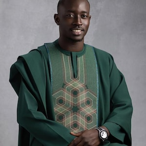 May include: A dark green traditional outfit with intricate embroidery on the chest. The outfit includes a long-sleeved tunic and matching trousers. A silver wristwatch with a black face is visible on the wrist.