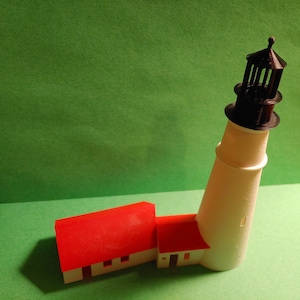 May include: A white and black lighthouse model with a red roof. The lighthouse is made of plastic and has a detailed design.