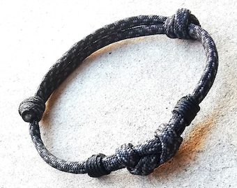 May include: A black braided rope bracelet with a knot design.