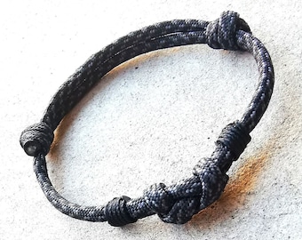 May include: A black braided rope bracelet with a knot design.