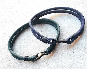 May include: Two paracord bracelets with black metal clasps. One bracelet is dark green and the other is dark blue.