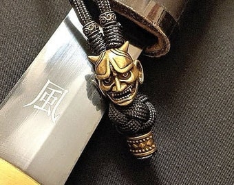 May include: A black sword with a gold-colored hilt and a black cord with a gold-colored oni mask charm. The sword has the kanji for "wind" inscribed on the blade.