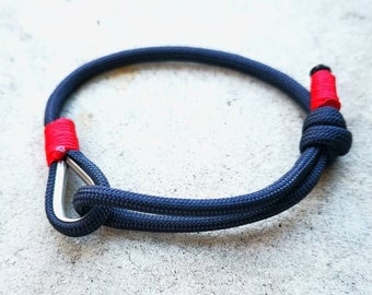 May include: A navy blue rope bracelet with red accents and a silver clasp.
