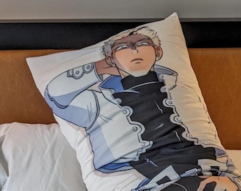 May include: A white body pillow with a printed image of a person wearing a white jacket, black pants, and boots. The person is lying on their side with their head resting on the pillow. The pillow is on a white bed.