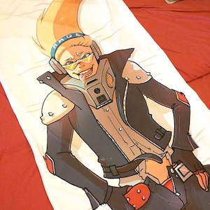 May include: A white pillowcase with a cartoon illustration of a character with blonde hair, yellow glasses, and a mask. The character is wearing a black jacket with red accents and black gloves. The pillowcase is on a red bed.