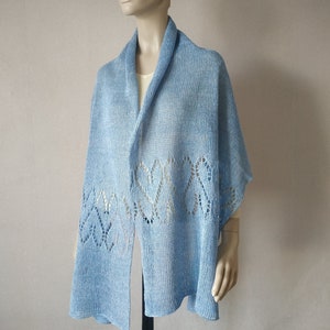 May include: A light blue knitted shawl with a delicate lace pattern around the edges.
