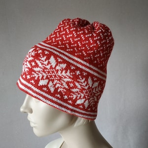 May include: Red knitted beanie with a white snowflake pattern. The beanie is folded down at the top.